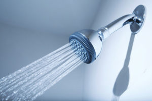 Shower head on the bathroom wall with water flowing out